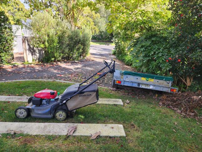 Mower and loaded green waste trailer on a Waihi driveway